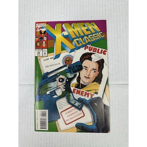 May include: X-Men Classic comic book featuring the title in yellow and blue, with a cover illustration of a woman and a man with a gun. The comic has the Marvel logo and the text "ENEMY".