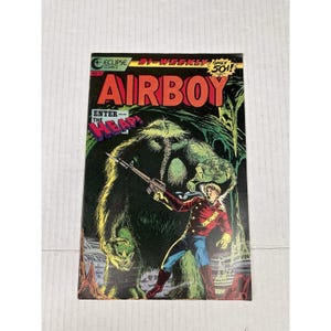 May include: A vintage comic book cover for "Airboy" features a dynamic illustration. A man in a red jacket and blue pants aims a rifle at a large, green, monstrous figure. The title "Airboy" is in bold red letters, with additional text.