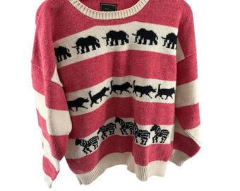 May include: A pink and white striped sweater with black animal silhouettes. The sweater features elephants, cats, and zebras. The neckline and cuffs are cream-colored.