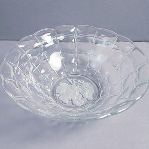 May include: Clear glass bowl with a diamond pattern and scalloped edges. The center of the bowl features a frosted grape design. This decorative bowl is suitable for serving fruit or as a decorative piece.
