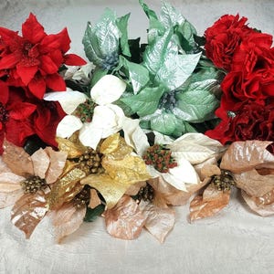 May include: A collection of artificial poinsettia flowers in various colors. The arrangement includes red, green, white, gold, and tan flowers, perfect for holiday decorations. The flowers have detailed petal textures.