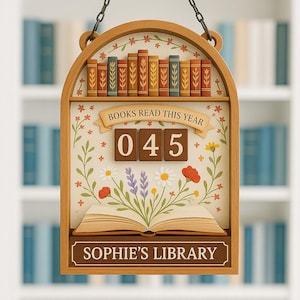 May include: Wooden sign with a decorative frame, featuring a miniature library scene. The sign displays the text "BOOKS READ THIS YEAR" above the number "045". The bottom of the sign reads "SOPHIE'S LIBRARY". The sign is hanging from a chain.