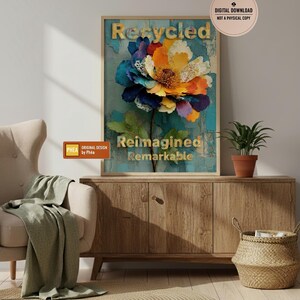 Peut inclure: Une affiche encadrée représentant une grande fleur colorée avec les mots "Recycled, Reimagined, Remarkable". La fleur a des pétales bleus, oranges et jaunes. L'affiche est affichée au-dessus d'un meuble en bois.