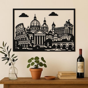 Puede incluir: Arte mural de metal negro que representa el horizonte de Roma, incluyendo el Coliseo y la Basílica de San Pedro. La obra de arte está enmarcada. Una botella de vino, plantas y libros están sobre una superficie de madera.