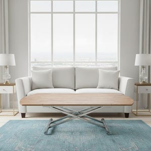 May include: A living room scene featuring a light wood lift-top coffee table with a metal base, a white sofa, two side tables with lamps, and a blue patterned rug. The room has large windows and white curtains.