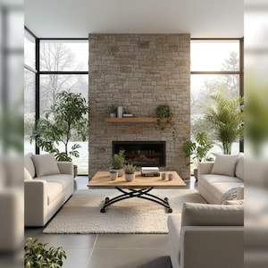 May include: A contemporary living room with a stone fireplace, two cream-coloured sofas, and a wooden coffee table. The room has large windows overlooking a snowy scene and several potted plants, creating a warm and inviting atmosphere.