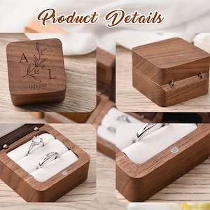 May include: Wooden ring boxes with a hinged lid, featuring a floral design and initials. The boxes are shown open, revealing rings nestled in white fabric. The text "Product Details" is visible.