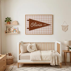 May include: A nursery scene with a white crib, wooden dresser, and a framed pennant that reads "Olivia June." The room has a neutral color palette with a rug, stuffed animals, and decorative shelves.