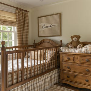 May include: A wooden crib with a brown and white checkered sheet and skirt, positioned next to a wooden dresser with a brown teddy bear. A framed wall print features a pennant design with the text Conrad Hayes in a brown checkered background.