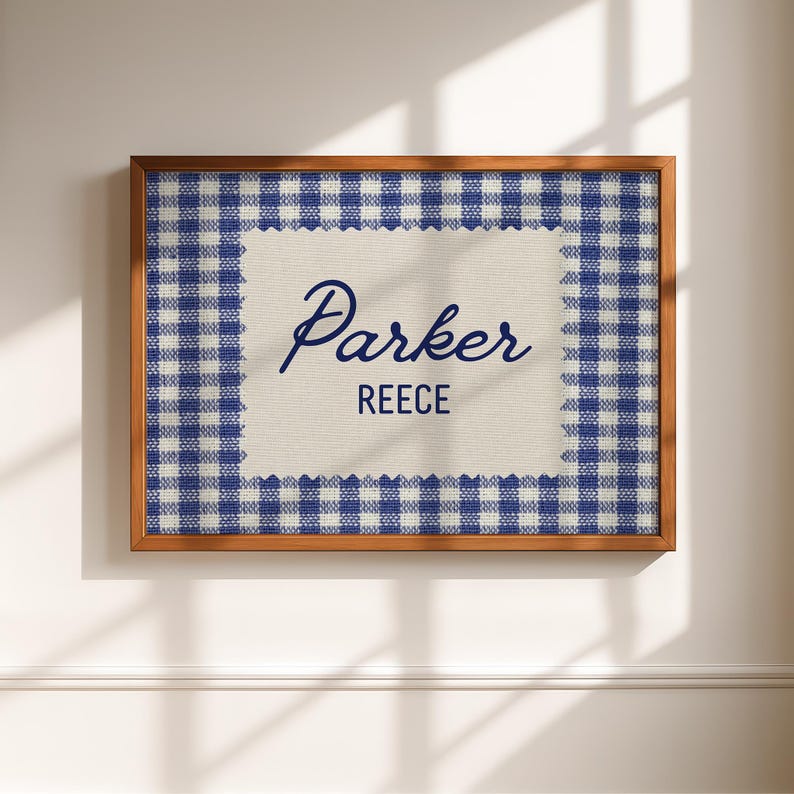 May include: A rectangular wall art piece in a wooden frame featuring a blue and white gingham border surrounding a central cream-colored fabric panel. The text 'Parker' is written in a blue script font above the word 'REECE' in blue block letters.