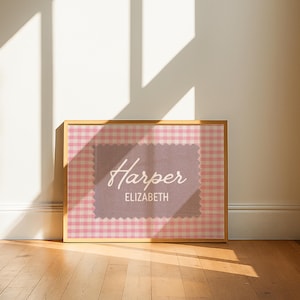 May include: A rectangular framed print featuring a pink and white gingham pattern background. Centered is a mauve-colored rectangular patch with scalloped edges, displaying the name Harper in white script and ELIZABETH in white block letters.
