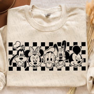 Op de afbeelding: Cr&egrave;mekleurige sweatshirt met een zwart-wit geblokt patroon en cartoonfiguren. De figuren zijn Goofy, Minnie Mouse, Donald Duck, Pluto en Mickey Mouse.