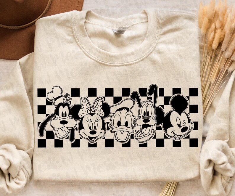 Op de afbeelding: Cr&egrave;mekleurige sweatshirt met een zwart-wit geblokt patroon en cartoonfiguren. De figuren zijn Goofy, Minnie Mouse, Donald Duck, Pluto en Mickey Mouse.
