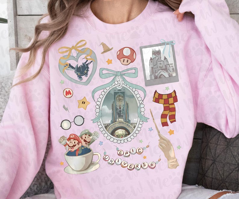 Pu&ograve; includere: Una felpa rosa chiaro con varie grafiche a cartoni animati. I disegni includono un cuore con un drago, un fungo, un castello, una sciarpa e la scritta "EPIC UNIVERSE". La felpa ha maniche lunghe e girocollo.