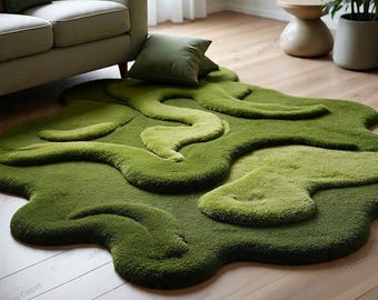 May include: A green, abstract-shaped rug with varying shades of green. The rug has a soft, plush texture and an organic, flowing design. It is placed on a light-colored wooden floor, creating a contrast in textures and colors.