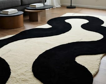 May include: A modern area rug with a cream-colored background and a bold, flowing black design. The rug's abstract pattern creates a striking contrast, adding a contemporary touch to the room's decor. The rug is made of a soft, plush material.