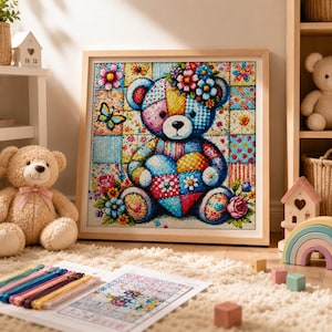 Pode incluir: Um kit de pintura de diamante quadrado com um urso de peluche patchwork colorido segurando um coração, rodeado por flores e borboletas. A obra está emoldurada em madeira clara e exibida com um guia de padrão impresso e fios coloridos.