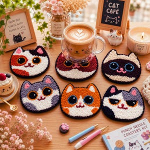 Puede incluir: Un juego de seis posavasos redondos de punch needle con varios rostros de gatos de diferentes colores y patrones de pelaje, incluyendo diseños de calicó, siamés y atigrado, exhibidos junto a una taza de cristal, bolígrafos y un kit.