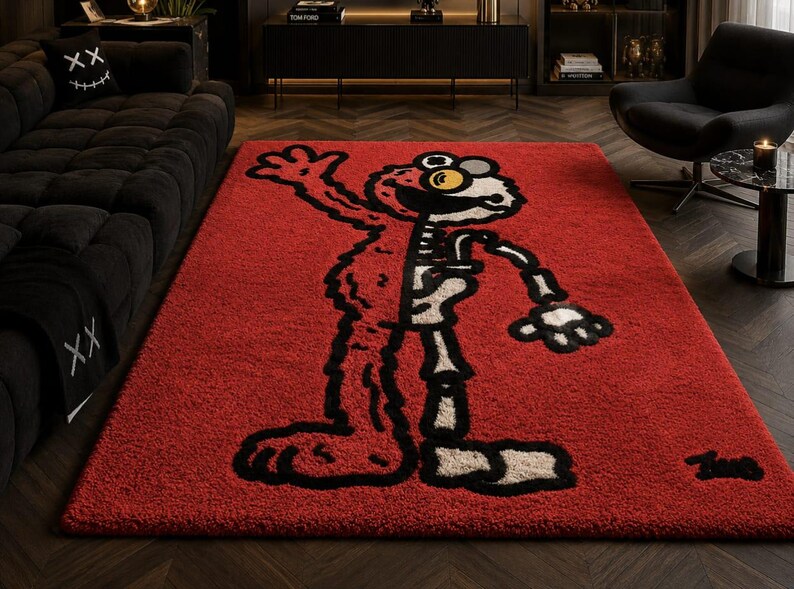 Puede incluir: Una alfombra rectangular roja con un dise&ntilde;o de personaje de dibujos animados. El dise&ntilde;o est&aacute; dividido, mostrando el exterior del personaje a la izquierda y un esqueleto a la derecha. El personaje tiene contornos negros, ojos amarillos y un esqueleto beige. La alfombra es de material suave y afelpado.