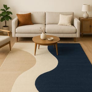 May include: A modern living room rug with a flowing design in beige, cream, and navy blue. The rug is placed in front of a beige sofa with brown and cream throw pillows. A wooden coffee table and side table complete the scene.