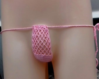 May include: A pink crochet thong with a net-like pouch. The thong features a thin, delicate waistband and a pouch with an open, airy design. The color is a soft, pastel pink, and the overall style is handmade.