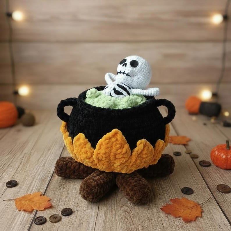 Crochet Halloween amigurumi pattern featuring a black plush cauldron with yellow flames, a bubbling green potion, and a cute white skeleton sitting inside. Perfect for spooky home décor, Halloween party centerpiece, or a handmade gift. This detailed crochet pattern is ideal for amigurumi lovers and includes step-by-step instructions. Great project for Halloween crafters looking for unique and fun holiday decorations.