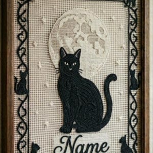 Könnte beinhalten: Ein gerahmtes Stickbild mit einer schwarzen Katze, die vor einem großen, strukturierten cremefarbenen Mond sitzt. Der Rand ist mit schwarzen Katzensilhouetten und Ranken verziert. Das Wort Name ist unten in schwarzer Schreibschrift gestickt.