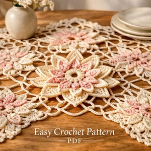 May include: A cream-colored, crocheted table runner with a floral design. The flowers are detailed with pink petals and a cream-colored center. The text "Easy Crochet Pattern - PDF" is at the bottom.