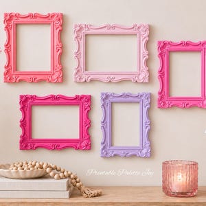 May include: A collection of five empty ornate picture frames in shades of coral, light pink, hot pink, magenta, and lavender. The frames feature intricate scrollwork and decorative molding, arranged in a gallery display on a neutral wall.