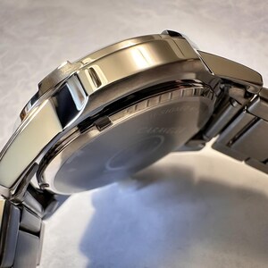 May include: A close-up of a silver wristwatch with a stainless steel band. The watch face is visible, and the band is connected to the watch case. The watch has a shiny, polished finish, reflecting the light. The watch is a classic style.