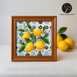 Peut inclure: Un motif de point de croix encadré représentant des citrons jaunes vifs avec des feuilles vertes et des fleurs blanches sur un fond à motifs bleu et blanc. Le cadre est en bois. Le texte "CROSS STITCH PDF PATTERN" est en bas.