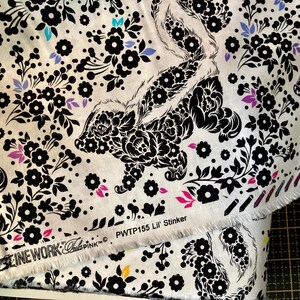 May include: White fabric with a repeating pattern of black skunks and floral designs. The skunks are stylized with floral patterns. Accents of purple, pink, and teal flowers are scattered throughout. The text "PWT155 Lil' Stinker" is visible.