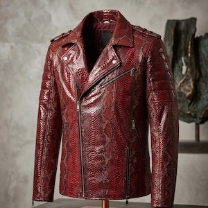 May include: A deep red motorcycle jacket featuring a textured snakeskin pattern. The jacket includes a wide notched collar, silver-toned metal zips on the front and pockets, shoulder epaulettes, and quilted detailing on the upper sleeves.
