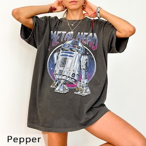 May include: Dark gray t-shirt with a graphic of R2-D2 from Star Wars, set against a space-themed background. The text "METAL HEAD" is above the droid. The shirt is labeled "Pepper" at the bottom.