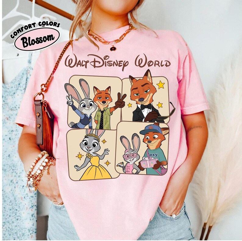 Peut inclure: T-shirt rose clair avec un motif des personnages du film Zootopie. Le design comprend Judy Hopps et Nick Wilde, avec le texte "Walt Disney World" et "Comfort Colors Blossom".