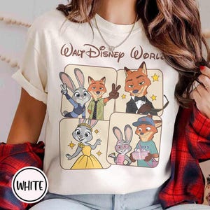 Peut inclure: T-shirt cr&egrave;me avec un graphisme des personnages du film Zootopie, dont Judy Hopps et Nick Wilde, avec le texte "Walt Disney World". Le t-shirt a un col rond et des manches courtes, avec le mot "WHITE" dans un cercle en bas.