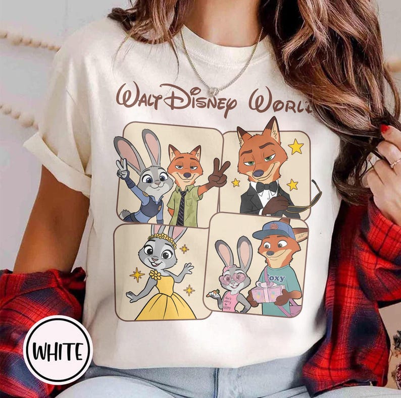 Peut inclure: T-shirt cr&egrave;me avec un graphisme des personnages du film Zootopie, dont Judy Hopps et Nick Wilde, avec le texte "Walt Disney World". Le t-shirt a un col rond et des manches courtes, avec le mot "WHITE" dans un cercle en bas.