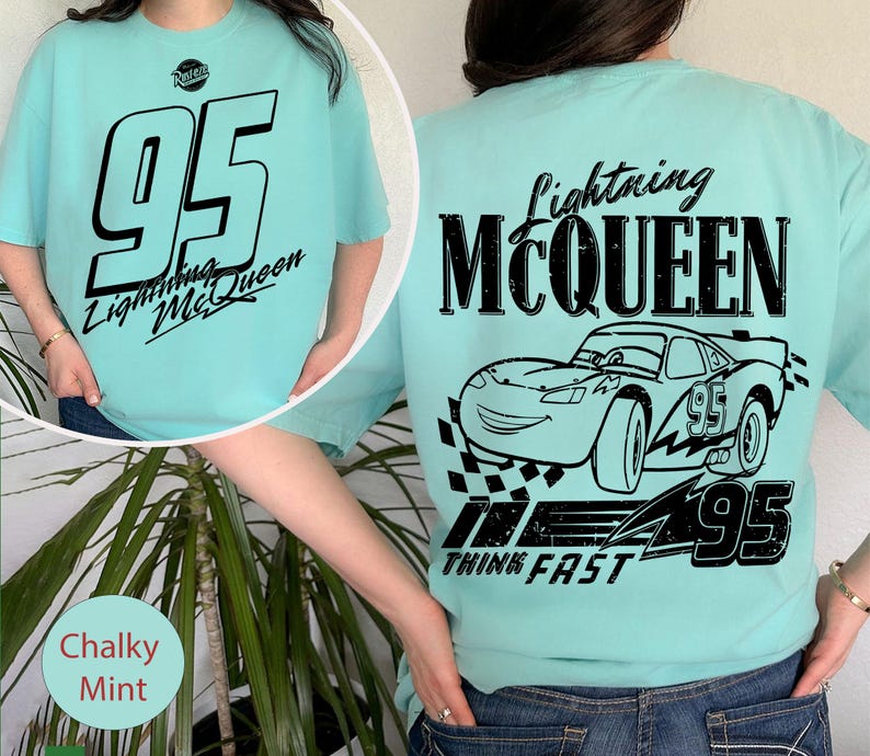 May include: A light teal t-shirt featuring the number 95 and the words "Lightning McQueen" in black on the front. The back of the shirt displays a graphic of Lightning McQueen, the number 95, and the words "Think Fast".