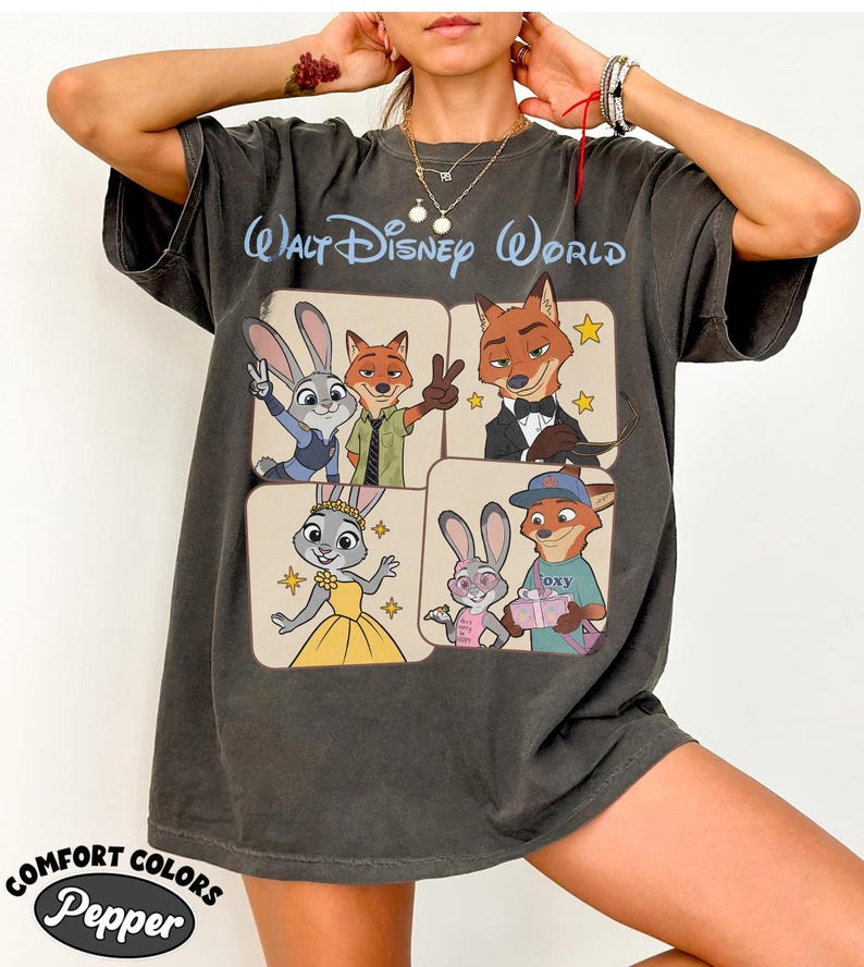 Peut inclure: T-shirt gris fonc&eacute; avec des personnages du film Zootopie. Le t-shirt porte les mots "Walt Disney World" en bleu clair en haut. Le coin inf&eacute;rieur gauche du t-shirt porte les mots "Comfort Colors Pepper".