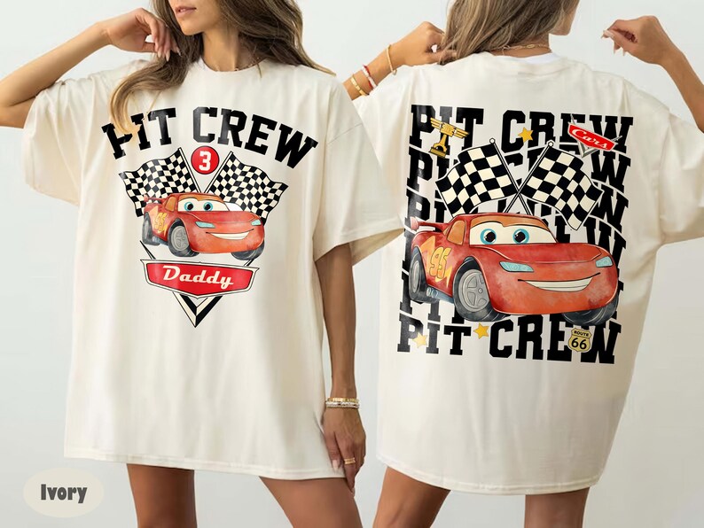 May include: Ivory-colored t-shirt featuring a graphic of a red race car with the text "PIT CREW" and "Daddy". The design includes checkered flags and the number 3. The back of the shirt also has the same design.