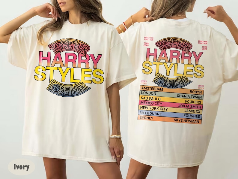 Pu&ograve; includere: Una t-shirt color avorio con una stampa grafica. La parte anteriore mostra il testo TOGETHER HARRY STYLES in rosa e giallo. Il retro presenta lo stesso testo sopra un elenco di citt&agrave; e nomi tra cui Amsterdam, London, Sao Paulo e Mexico City.