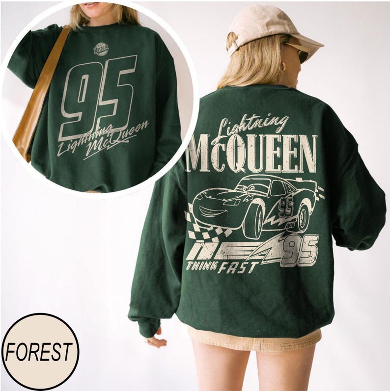 May include: Forest green sweatshirt featuring a Lightning McQueen graphic. The front displays the number 95 and the words "Lightning McQueen". The back has a large graphic of the race car, the words "Lightning McQueen", and the phrase "Think Fast".