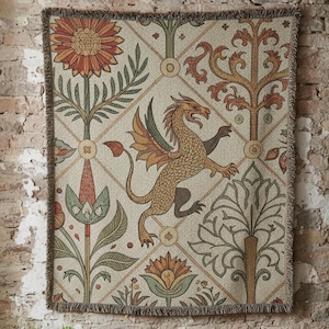 May include: A tapestry with a dragon design, featuring a beige background with a repeating diamond pattern. The dragon is gold with orange wings. The tapestry is fringed and hangs on a brick wall. Below, a wooden table displays framed botanical prints.