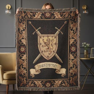 May include: A dark woven throw blanket with a heraldic design. The blanket features a shield with a lion, crossed swords, and the name "Brennan" on a banner. The border has a floral pattern.