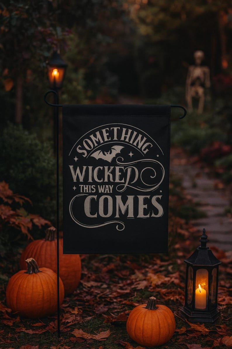 May include: A black Halloween garden flag with the text "SOMETHING WICKED THIS WAY COMES" in white script. The scene includes orange pumpkins, a lit lantern, and a pathway with a skeleton decoration in the background.