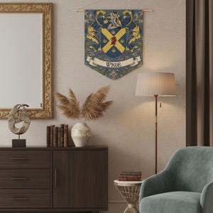 May include: A decorative wall hanging featuring a family crest design. The crest is primarily blue and gold, with a shield shape and the name "WADE" displayed on a banner. The crest is hanging on a wall in a room with a lamp, chair, and other decor.