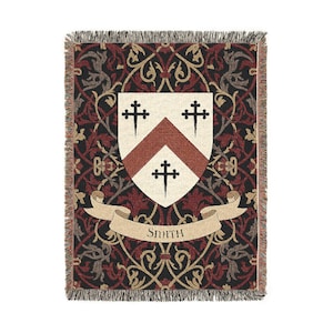 May include: Woven throw blanket with a heraldic crest design. The blanket features a cream-colored shield with a red chevron and three black crosses. The background is a dark red and black floral pattern, with the name "Smith" on a banner.