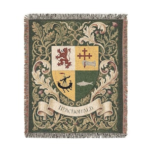 May include: A woven throw blanket with a green background and a central crest design. The crest features a shield divided into four sections, with a lion, cross, boat, and fish. The word "MACDONALD" is displayed on a banner.
