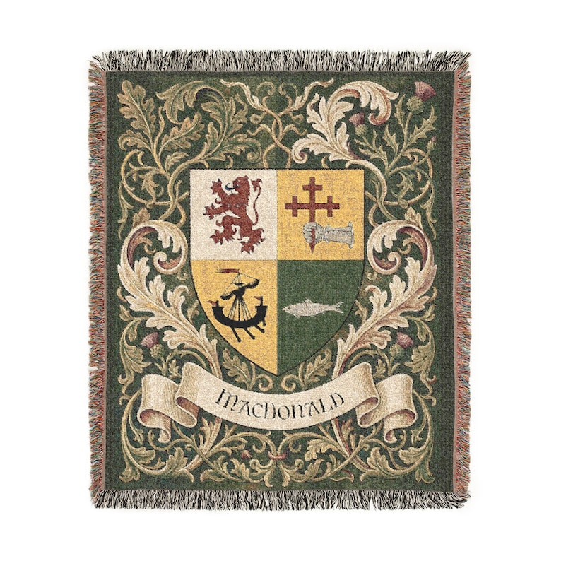 May include: A woven throw blanket with a green background and a central crest design. The crest features a shield divided into four sections, with a lion, cross, boat, and fish. The word "MACDONALD" is displayed on a banner.