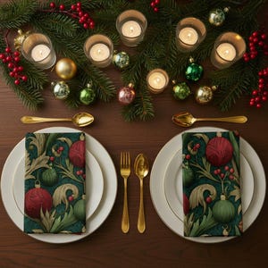 May include: A festive table setting with white plates, gold cutlery, and patterned napkins featuring red and green ornaments. Lit candles, evergreen branches, and red berries complete the holiday decor. Gold spoons and forks are placed on either side of the plates.